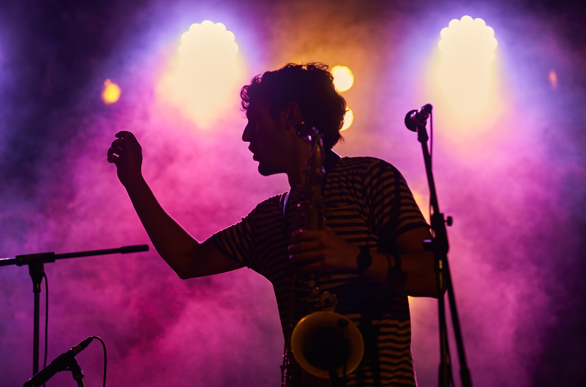 Silhouette of a saxophone player with pink and purple lights and smoke