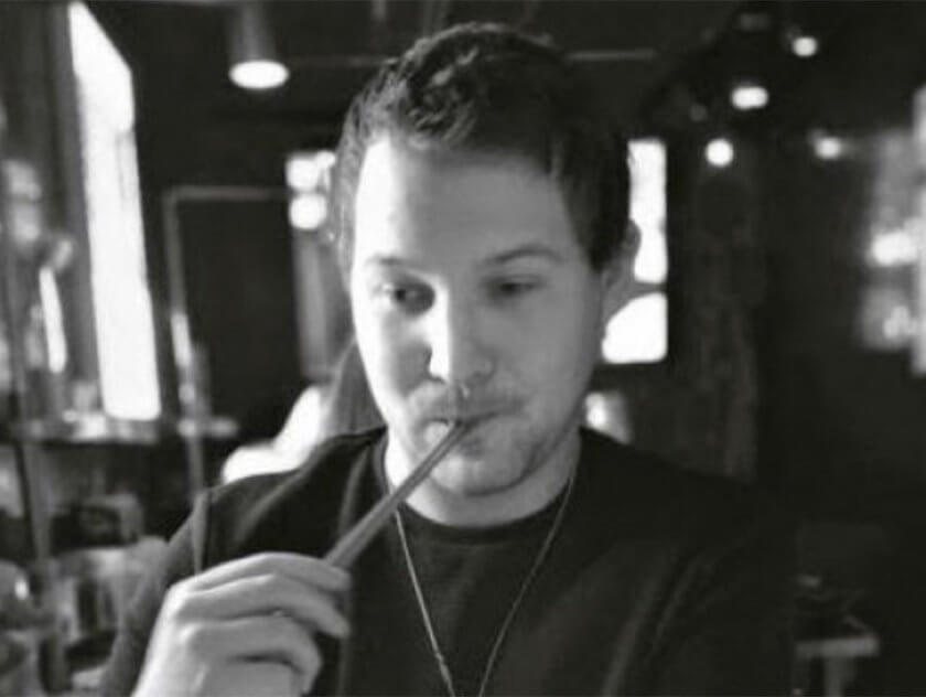 Black and white photo of man with a straw in his mouth