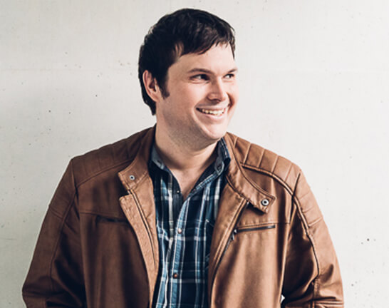 Nathan_Jensen Man wearing brown leather jacket, smiling.