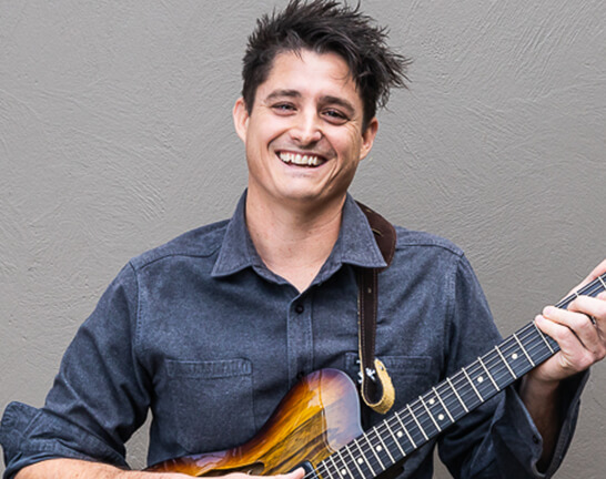 Man smiling, holding an electric guitar
