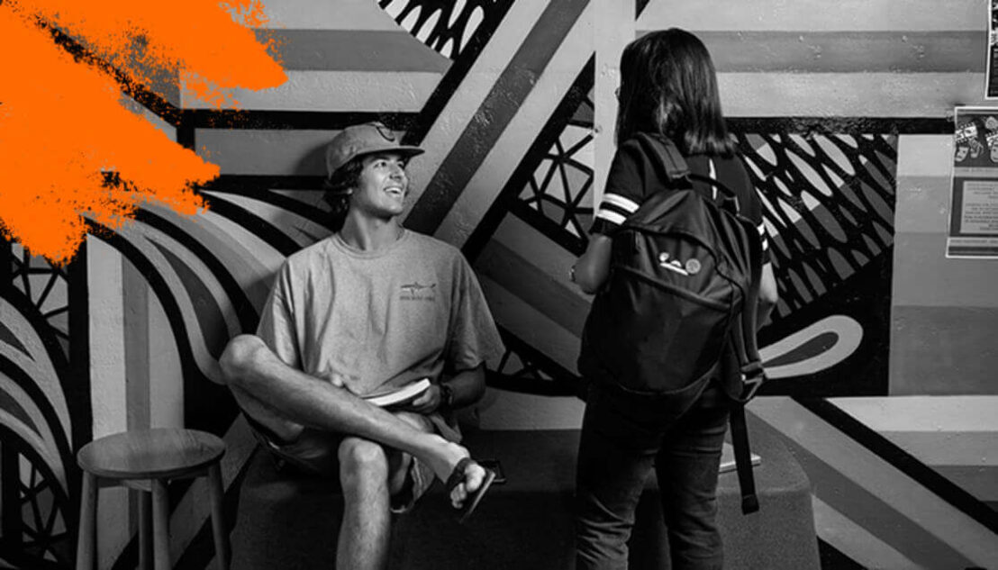 Two students talking in front of graffiti wall