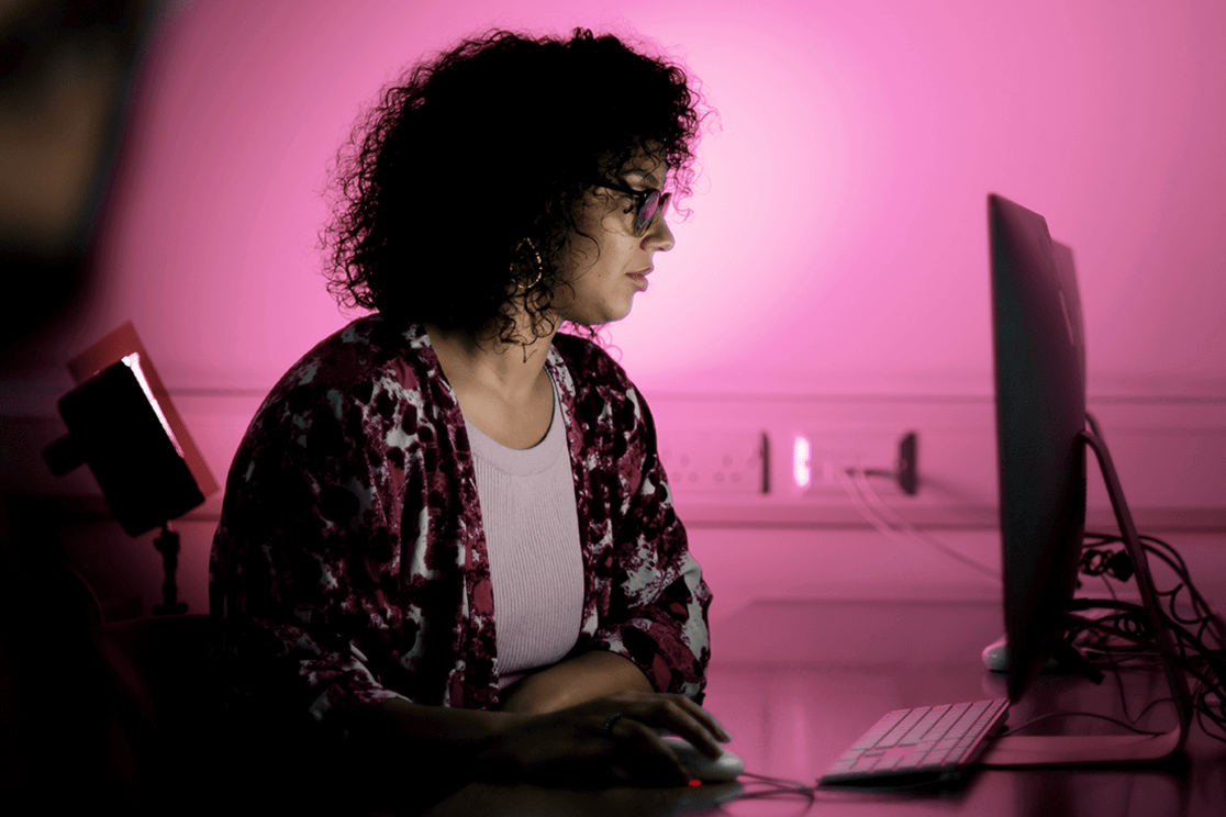 Woman working on computer in a pink-lit studio