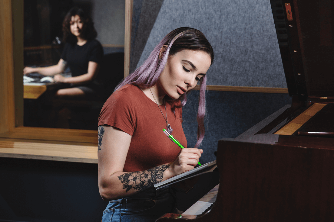Woman writing music by piano