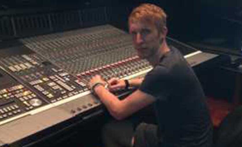 Man sitting at console desk looks over shoulder at camera