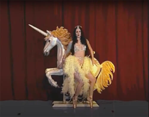 Burlesque performer next to unicorn prop
