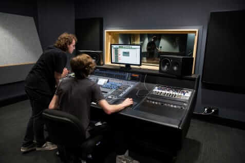 Students working in a sound booth. SAE students on audio desk