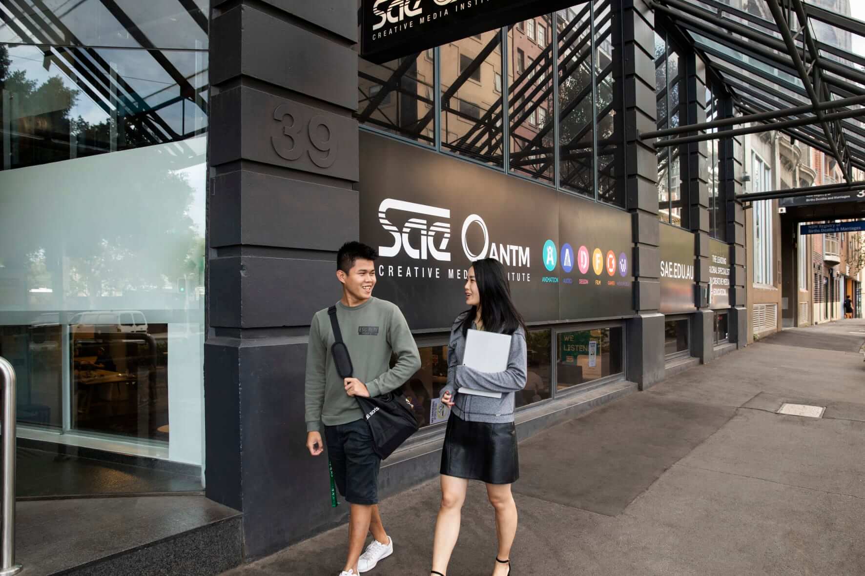 Two students walk outside the front of SAE campus in Sydney.