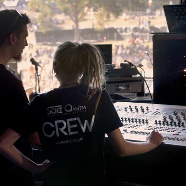 male and female SAE student at audio sound desk backstage and on work placement at Splendour In the Grass music festival.