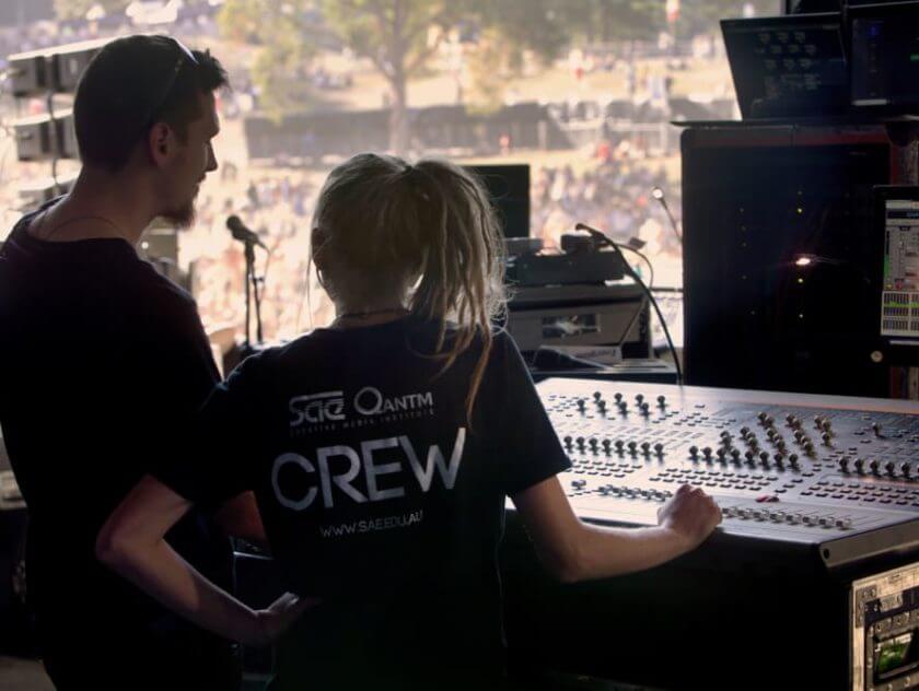 male and female SAE student at audio sound desk backstage and on work placement at Splendour In the Grass music festival.