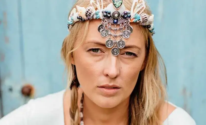 Woman wears an elaborate head piece with shells, stones, and chain mail.