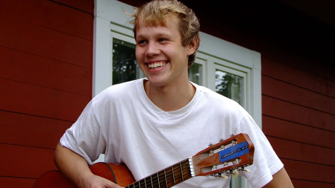 Student smiling, holding guitar