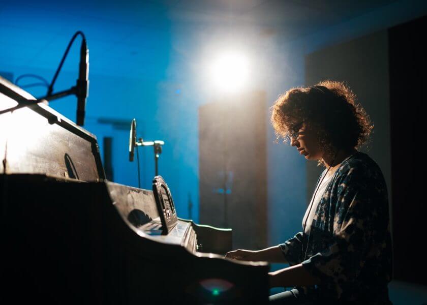 SAE Music student sits at piano with microphone in studio