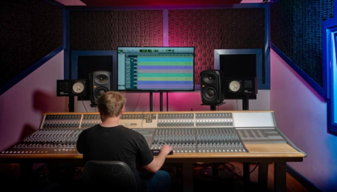 Person sitting in audio studio, working on equipment