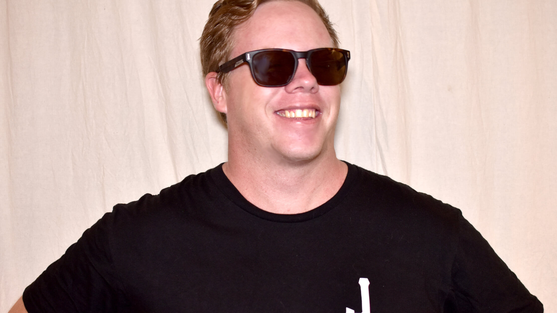 Man smiling, wearing black tshirt with white J on it.