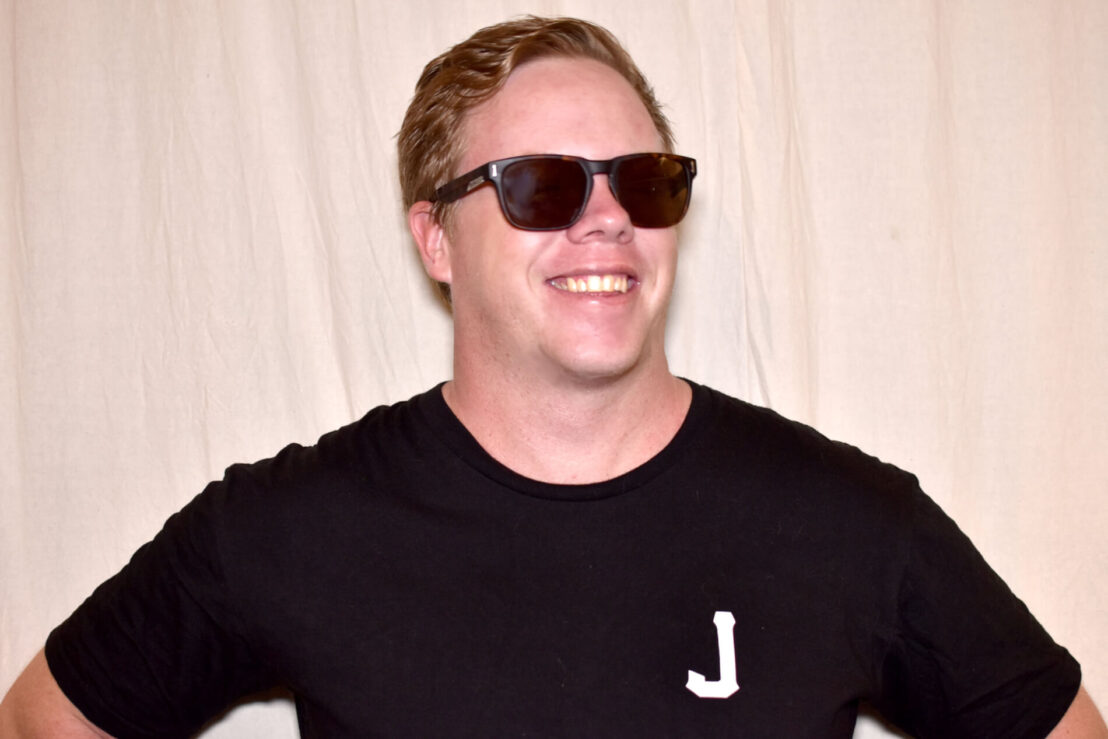 Man smiling, wearing black tshirt with white J on it.