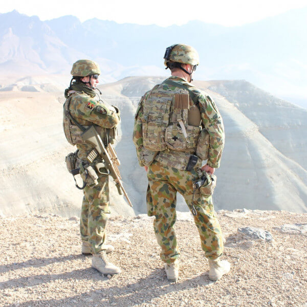 Man and woman standing in full combat gear, overlooking a canyon