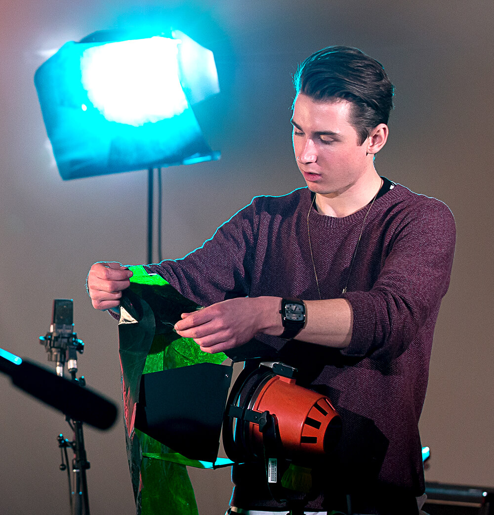 Student adjusting the lighting on set