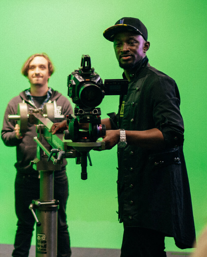 Man operating camera with green screen in background