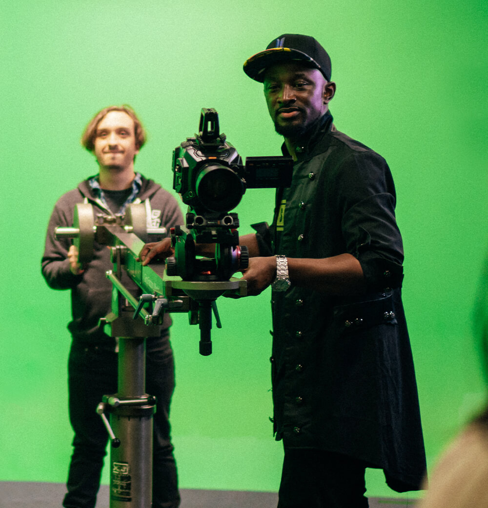 Man operating camera with green screen in background