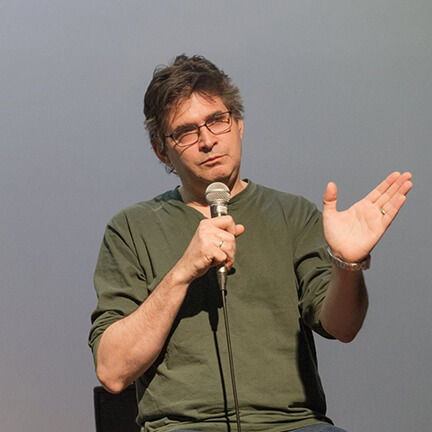 Man talking into a microphone with hand up