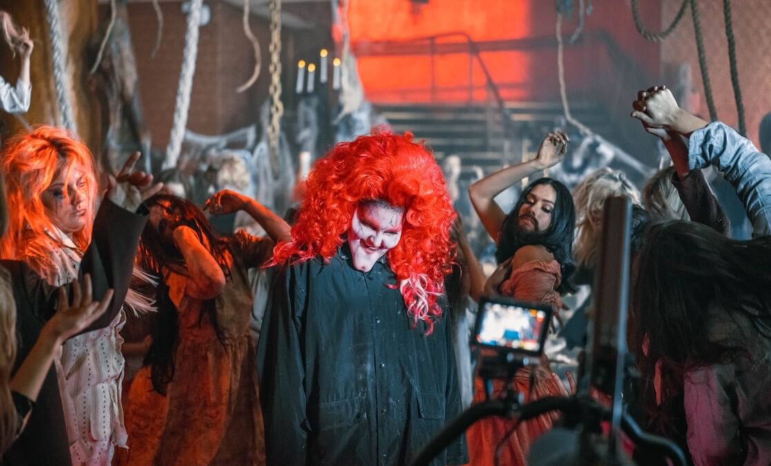 Aria nominated music video. behind the scenes. Woman wearing mask and wig in front of actors/extras in zombie like clothing