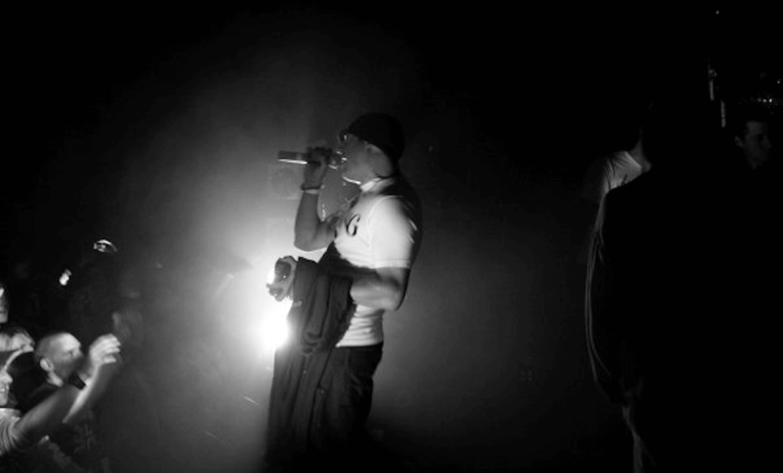 Black and white image of man performing on stage.