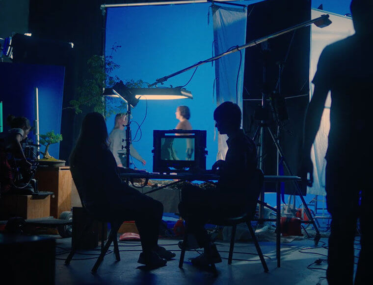People on a film set with a blue backdrop