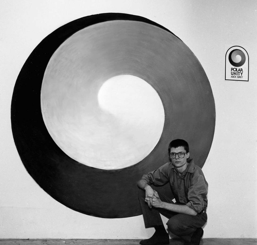 Black and white image of man kneeling in front of swirl painting