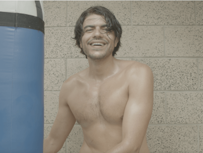 Man with no shirt in front of boxing bag