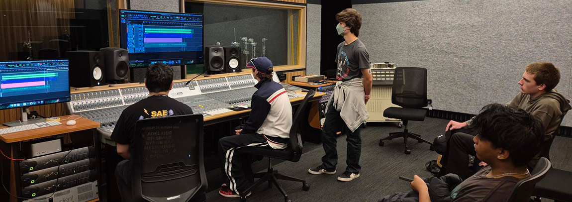 Five students at a Create for a day event on campus, using audio engineering equipment together
