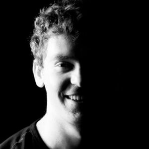 Man in black and white photo. Half face revealed. Other half in shadows. Andrew Kellie