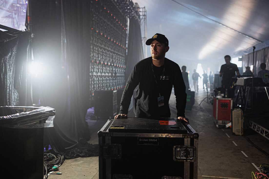 Man pushing audio equipment back of stage at live performance