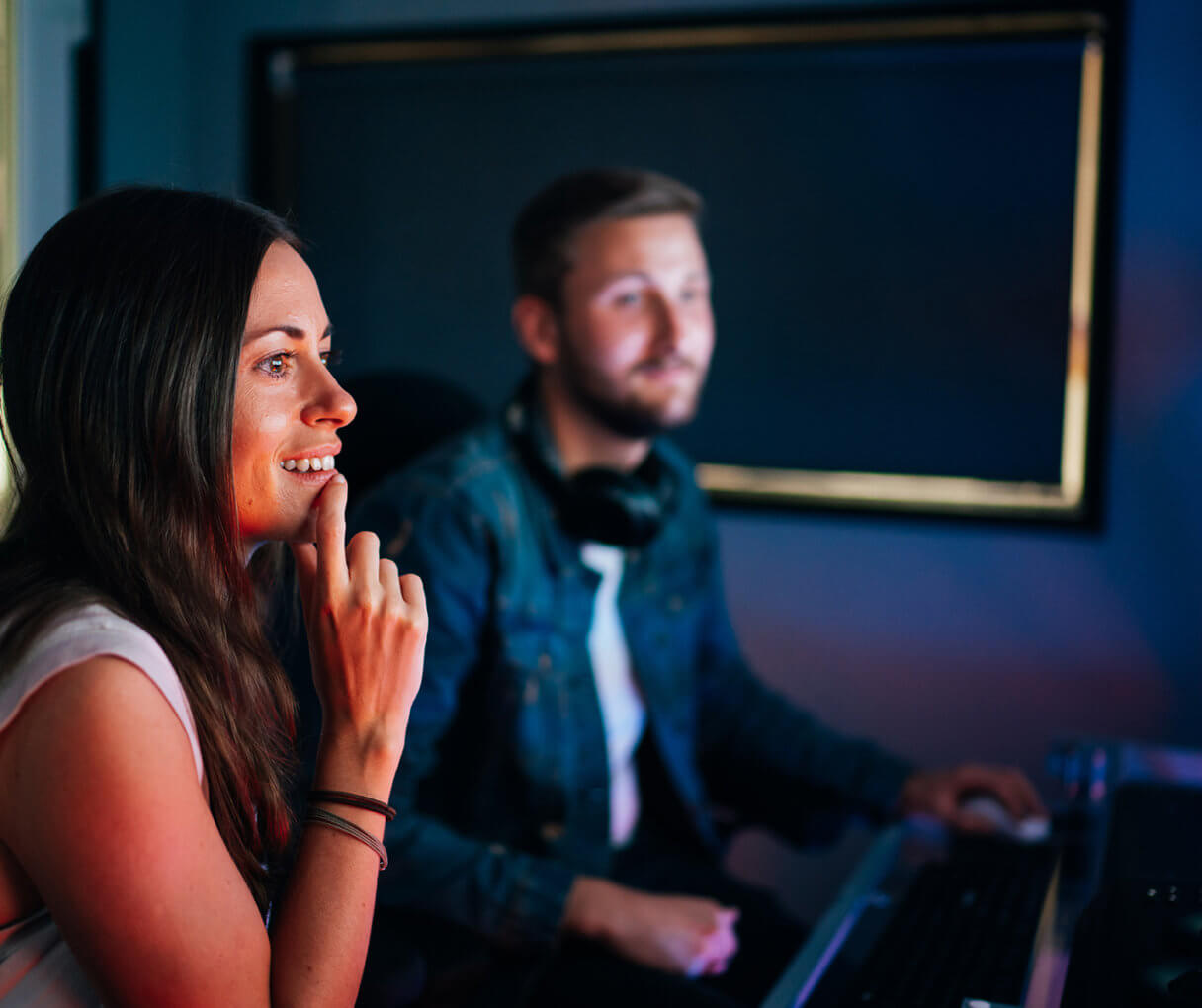 Girl and guy sit in front of screen
