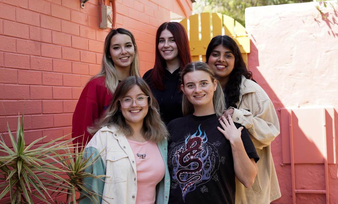 A group of young women and filmmakers stand together smiling at camera