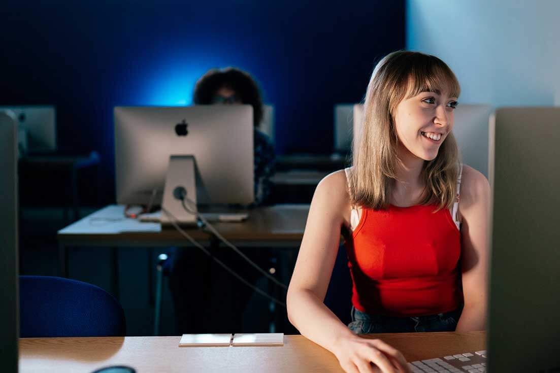 Girl sitting at desk in front pf desktop computer in study lab