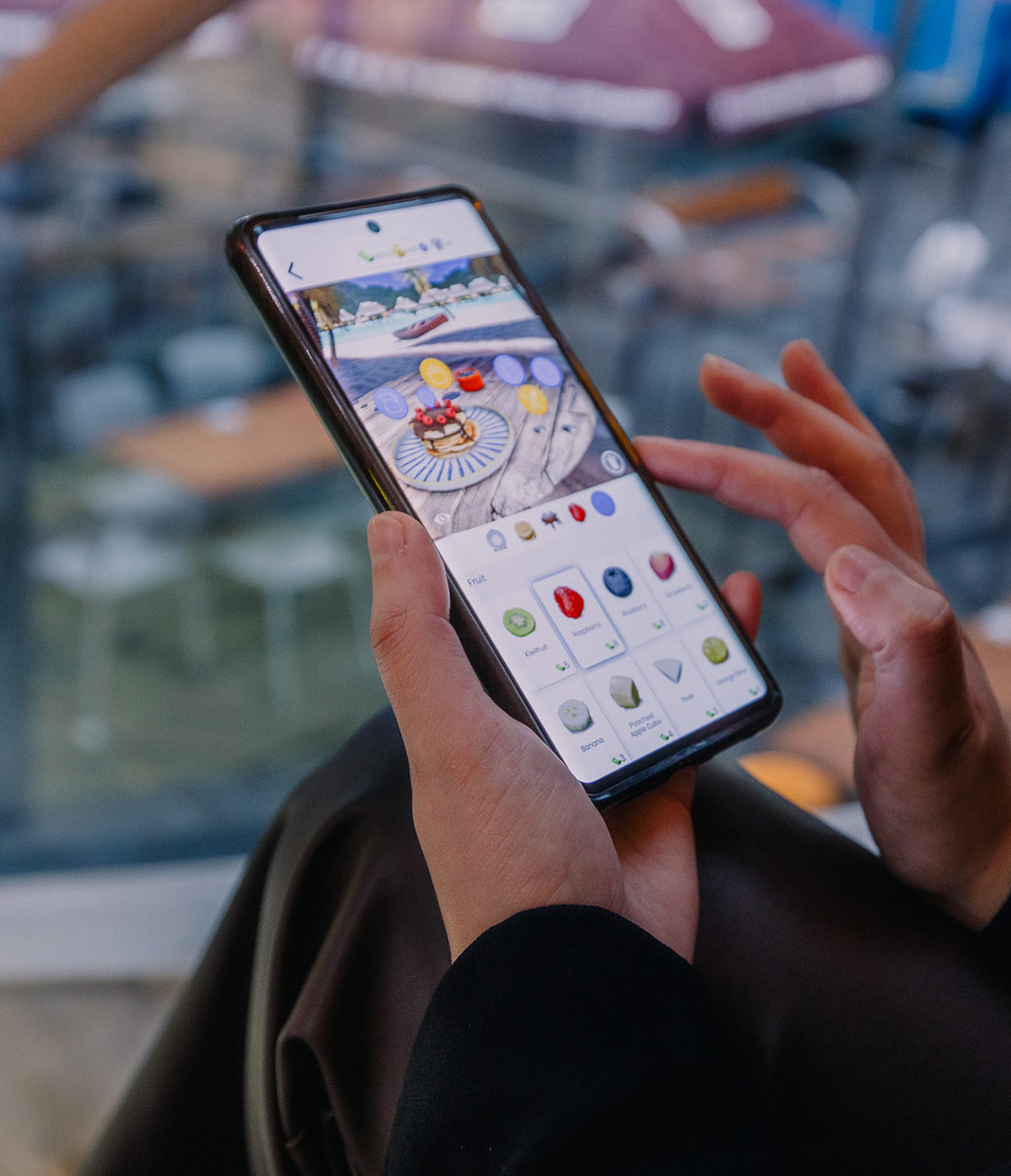 A close up image of Rachel Toomeh's hands holding an Android phone with a mobile game displaying on the screen