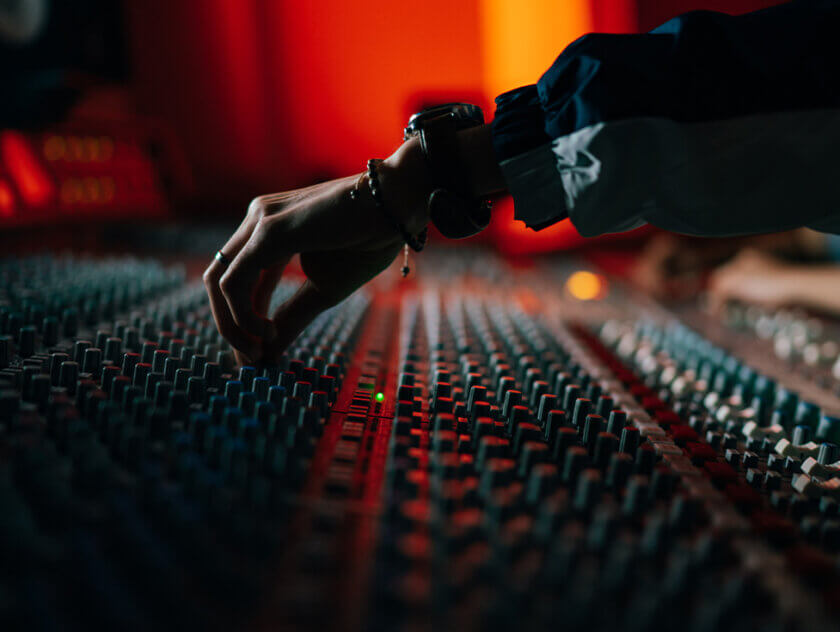 Persons hand adjusting knobs of a mixing analogue audio console