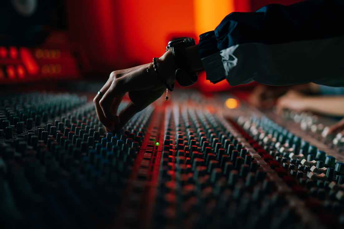 Persons hand adjusting knobs of a mixing analogue audio console