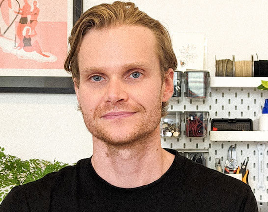 MAN SMILES AT CAMERA. SAE ALUMNI AND INVENTOR LUKE ELLIOTT