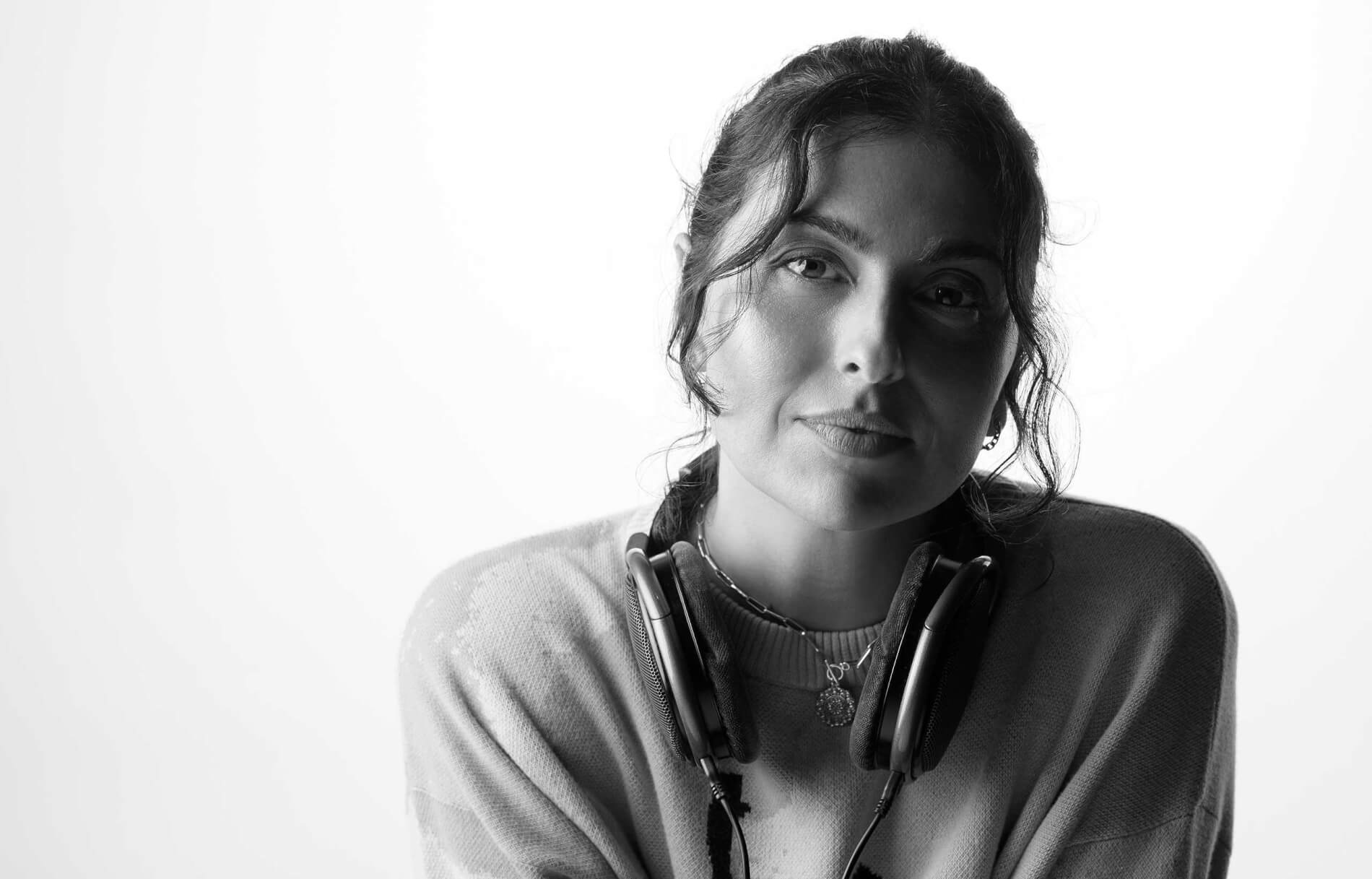 DJ and electronic music producer, Anna Lunoe sits with headphones around her neck.