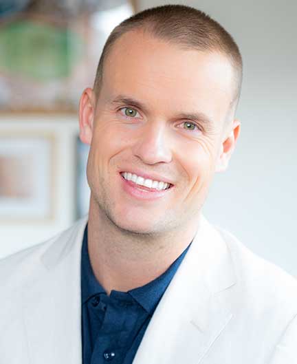 Portrait image of man who wears white jacket and navy blue shirt. Film maker and SAE graduate Josh King