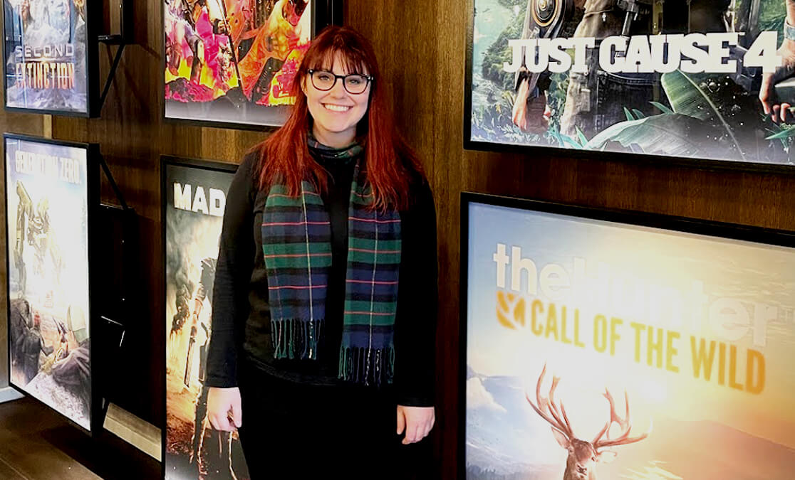 Woman smiling standing in front of video games posters