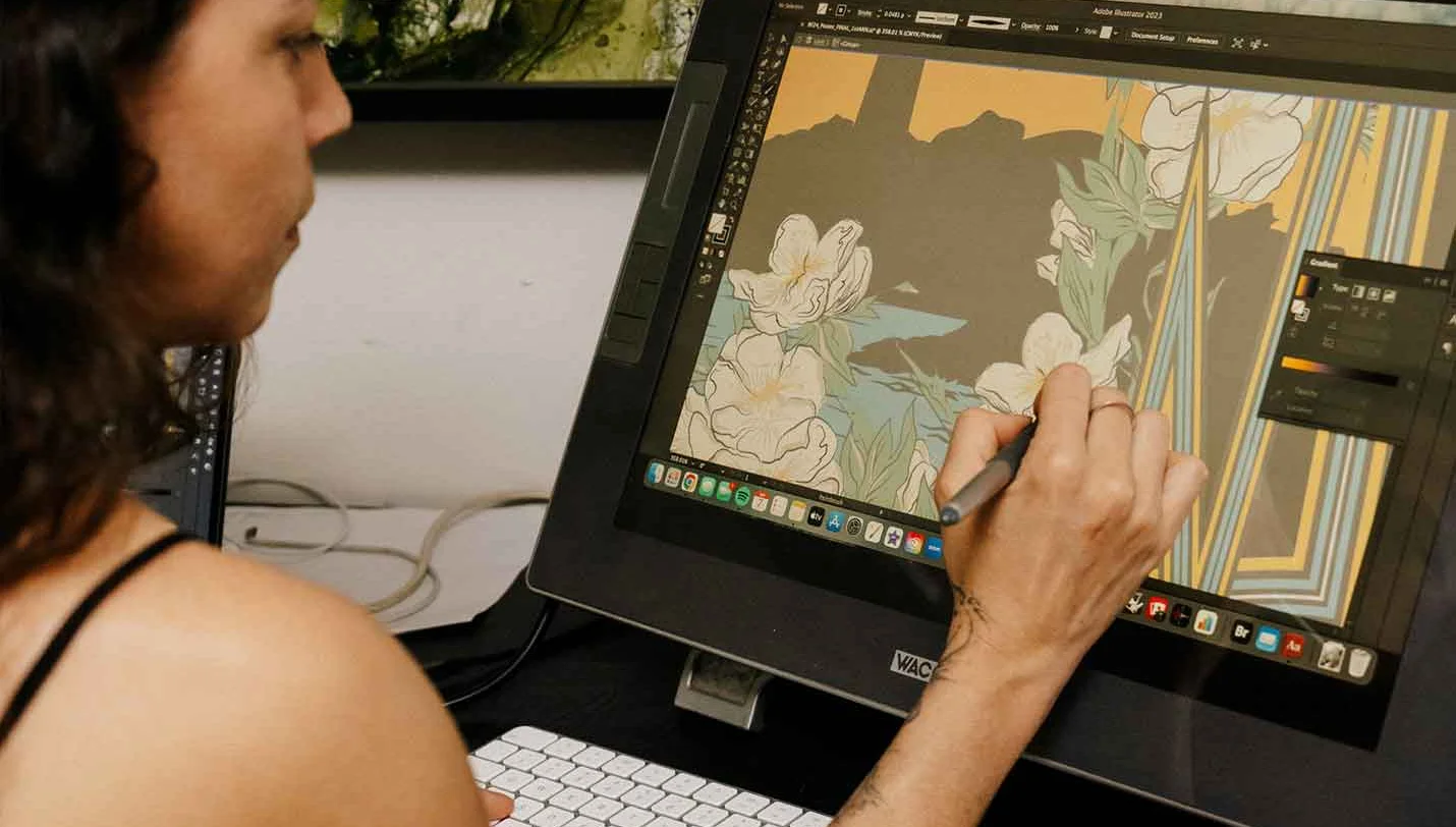 Girl with tattoos draws with a stylus on a wacom tablet screen. Illustrations and software appear on the monitor