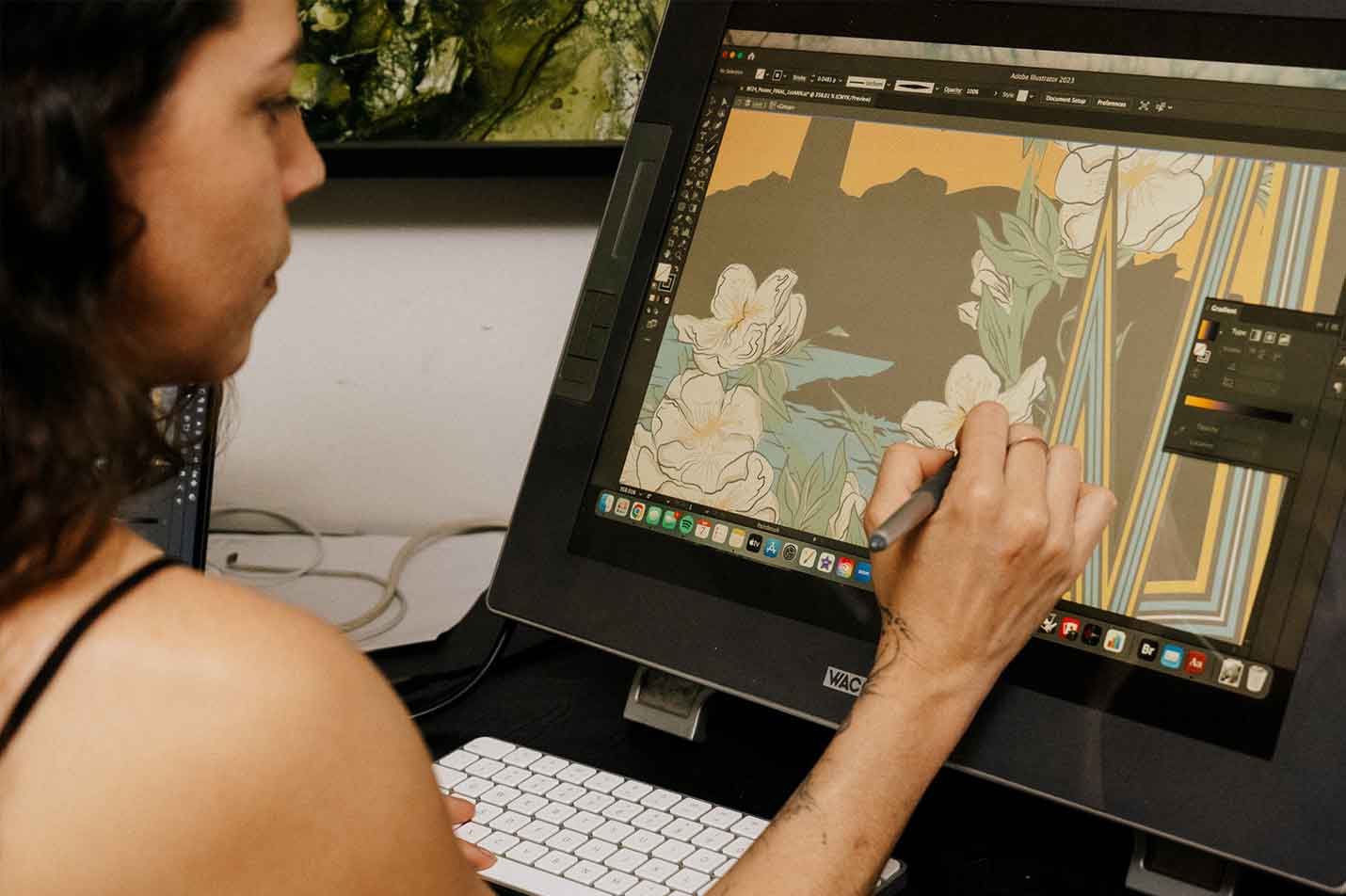 Girl with tattoos draws with a stylus on a wacom tablet screen. Illustrations and software appear on the monitor