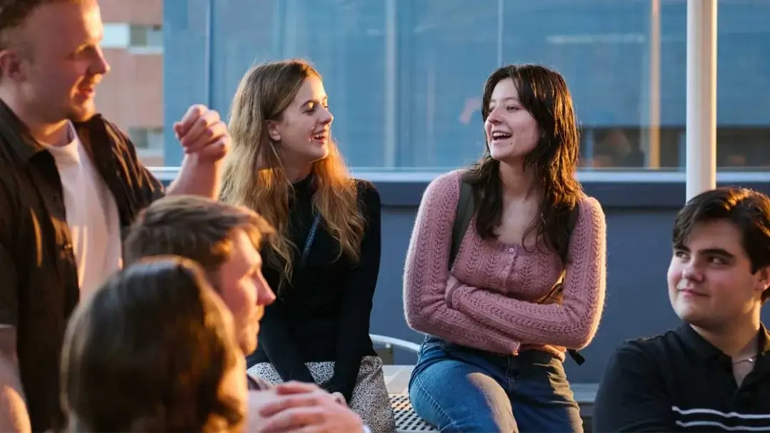 Group of people sit and stand. Candid image of group in conversation