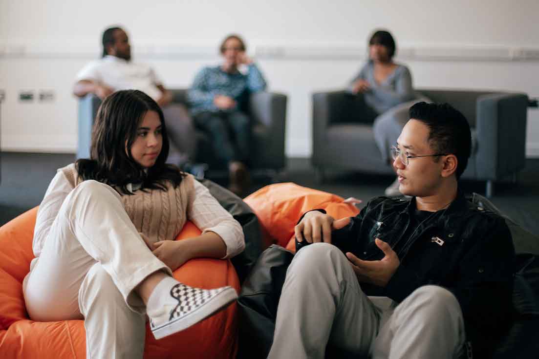 Two students sitting on beanbags discussing project and ideas. Collaborating and communicating