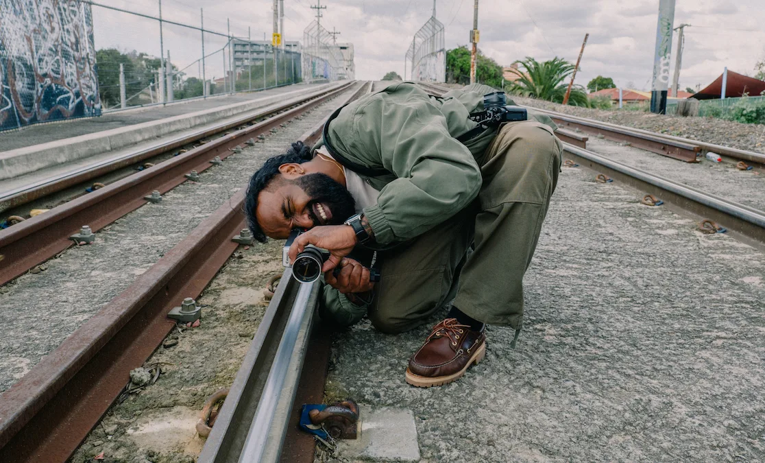 Man using film camera on train tracks