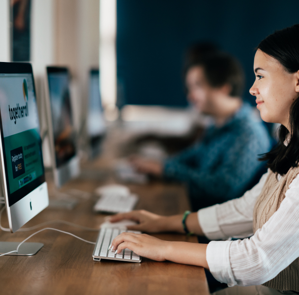 A woman at a long desk working on an iMac computer