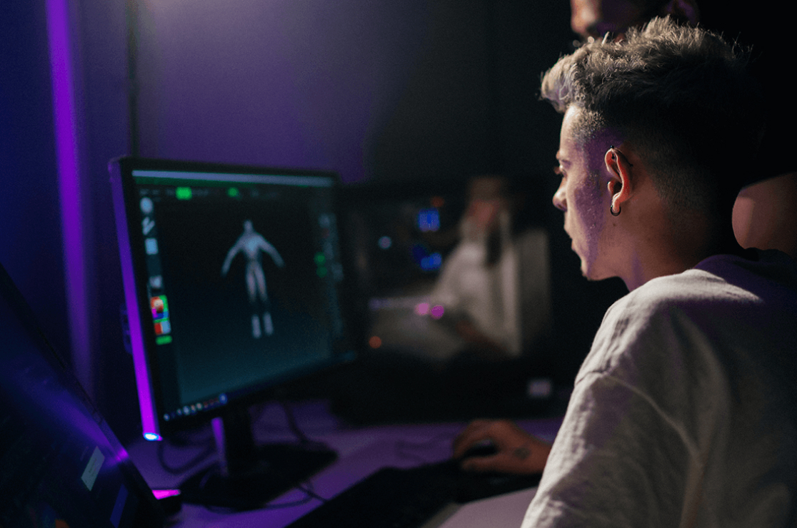 Male student looking at monitor screen in a dark room