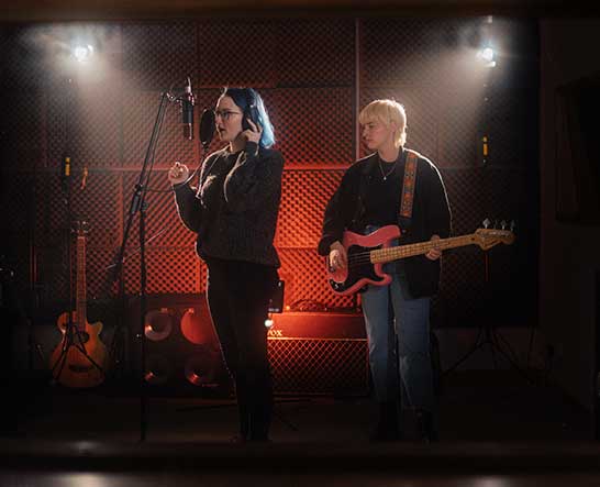 Two females in recording studio - singing and guitar